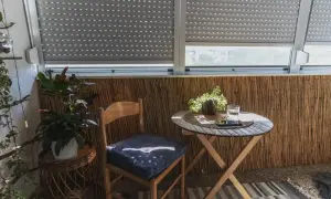 Przytulna loggia z drewnianym krzesłem i stolikiem. Rośliny dodają uroku temu balkonowi.