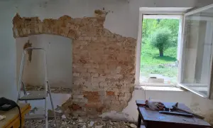 Ekspertyza budowlana starego domu: odsłonięta cegła, drabina i narzędzia wskazują na remont.