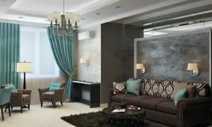 Eleganckie kolory w mieszkaniu: turkusowe zasłony, brązowa sofa i wzorzyste poduszki tworzą przytulną atmosferę.