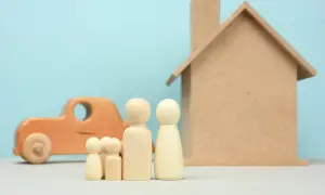 Drewniana rodzina, dom i samochód symbolizują marzenia o stabilności, ale też potencjalne zadłużenia BIK, które mogą je utrudnić.
