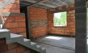 Wnętrze w budowie, widoczna klatka schodowa i ściany z pustaków ceramicznych. Trwa samowolne przekształcenie budynku gospodarczego na mieszkalny.