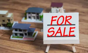 Modele domów na sprzedaż. Czy można sprzedać dom z kredytem? Tabliczka "FOR SALE" na sztaludze.