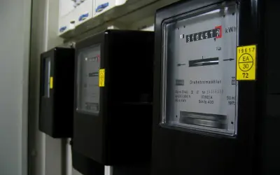 Trzy liczniki energii elektrycznej, jeden z nich pokazuje 310457.7 kWh. To może być podstawa do wyliczenia średniego rachunku za prąd w mieszkaniu.