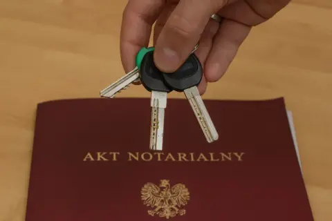 Klucze do nowego domu leżą na akcie notarialnym, który potwierdza akt własności.