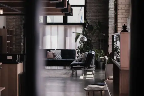 Nowoczesne wnętrze z czarną kanapą, designerskimi lampami i roślinami. To przykład, co to są ruchomości w aranżacji wnętrz.