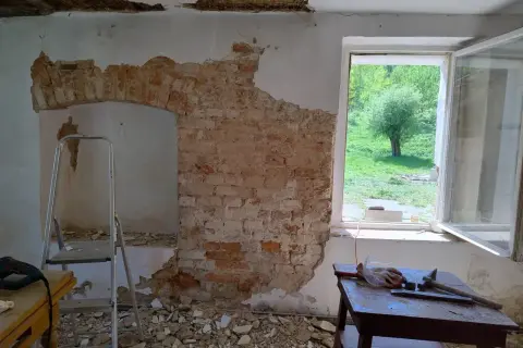 Ekspertyza budowlana starego domu: odsłonięta cegła, drabina i narzędzia wskazują na remont.