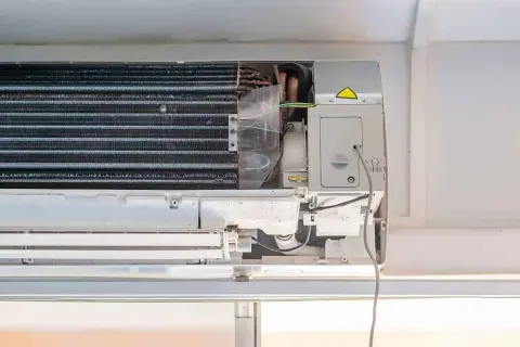 Wnętrze klimatyzacji w mieszkaniu, widoczne żeberka chłodzące i przewody.