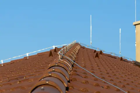 System piorunochronów na brązowym dachu. Czy piorunochron jest obowiązkowy? Instalacja chroni przed uderzeniami pioruna.