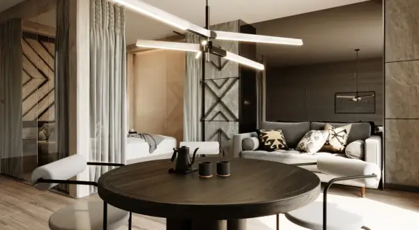 Nowoczesny apartament inwestycyjny z częścią sypialnianą oddzieloną zasłonami, salonem z szarą sofą i okrągłym stołem jadalnianym.