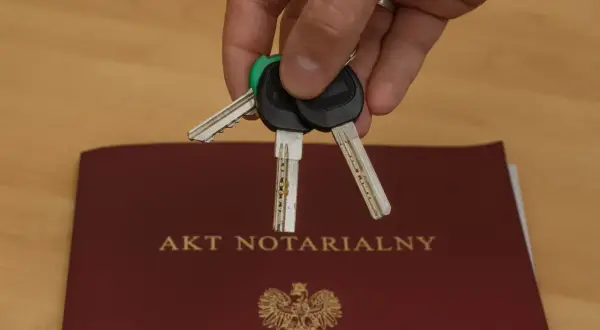 Klucze do nowego domu leżą na akcie notarialnym, który potwierdza akt własności.