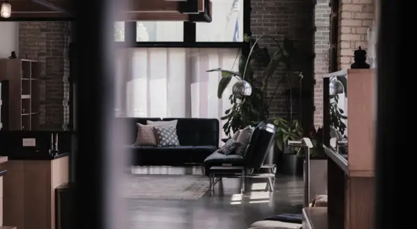 Nowoczesne wnętrze z czarną kanapą, designerskimi lampami i roślinami. To przykład, co to są ruchomości w aranżacji wnętrz.