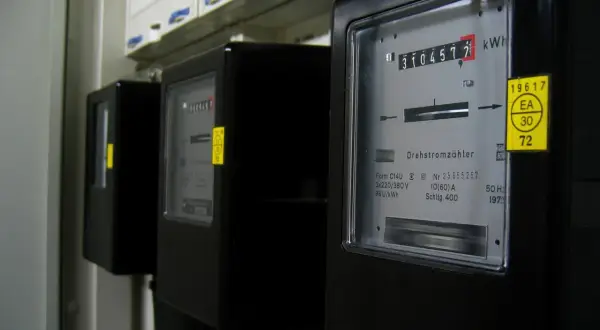 Trzy liczniki energii elektrycznej, jeden z nich pokazuje 310457.7 kWh. To może być podstawa do wyliczenia średniego rachunku za prąd w mieszkaniu.
