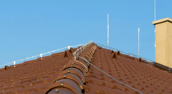 System piorunochronów na brązowym dachu. Czy piorunochron jest obowiązkowy? Instalacja chroni przed uderzeniami pioruna.