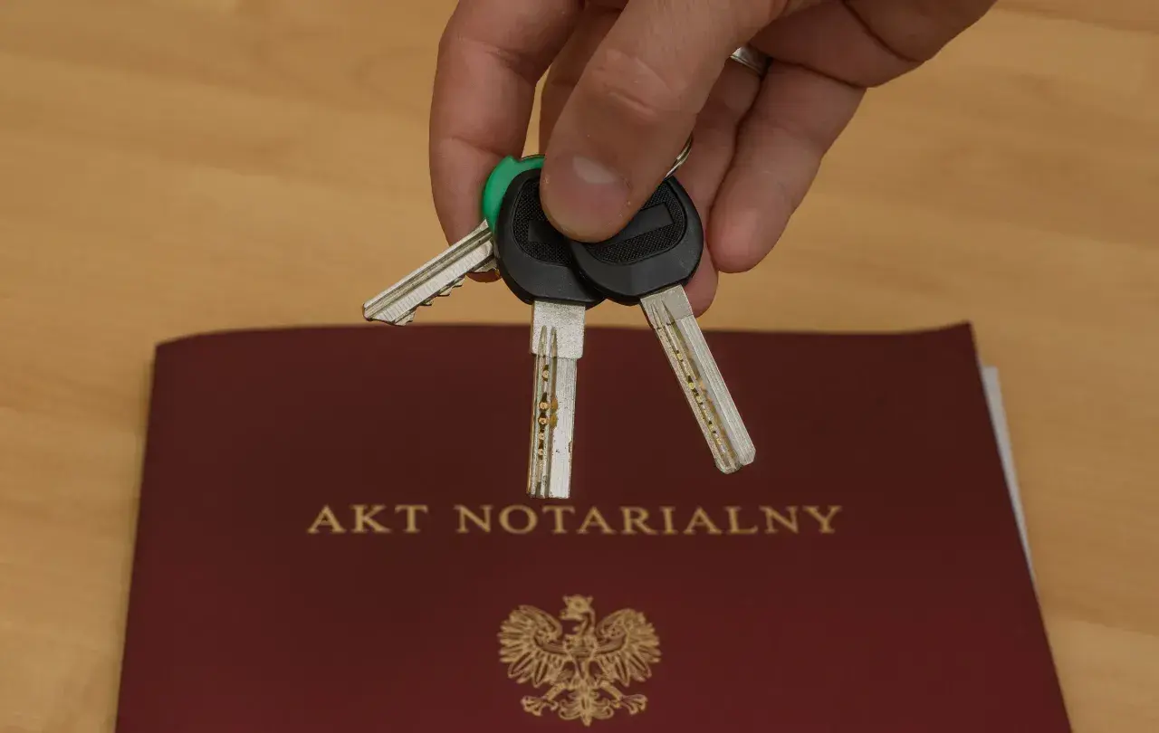 Klucze do nowego domu leżą na akcie notarialnym, który potwierdza akt własności.