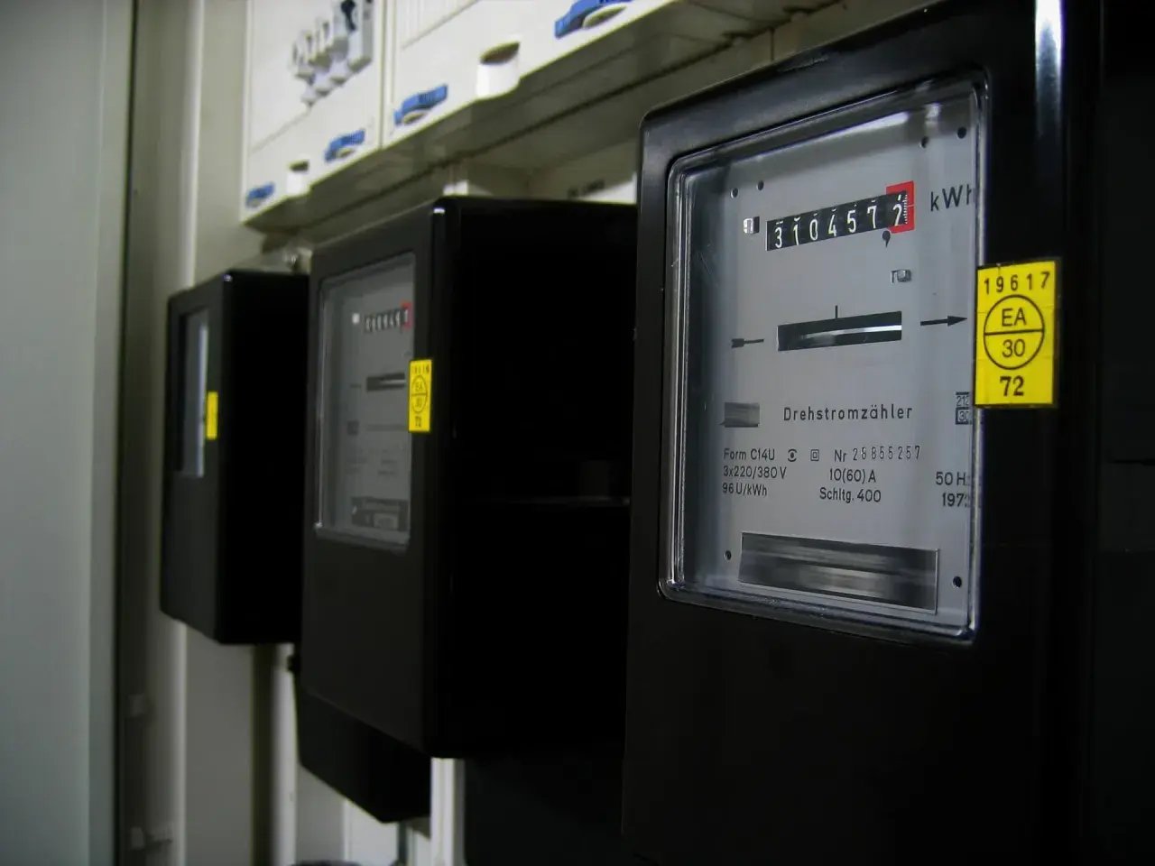 Trzy liczniki energii elektrycznej, jeden z nich pokazuje 310457.7 kWh. To może być podstawa do wyliczenia średniego rachunku za prąd w mieszkaniu.
