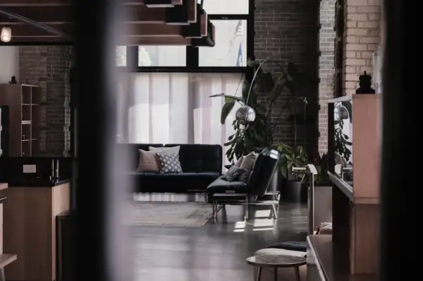 Nowoczesne wnętrze z czarną kanapą, designerskimi lampami i roślinami. To przykład, co to są ruchomości w aranżacji wnętrz.