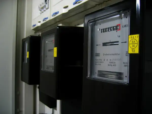 Trzy liczniki energii elektrycznej, jeden z nich pokazuje 310457.7 kWh. To może być podstawa do wyliczenia średniego rachunku za prąd w mieszkaniu.